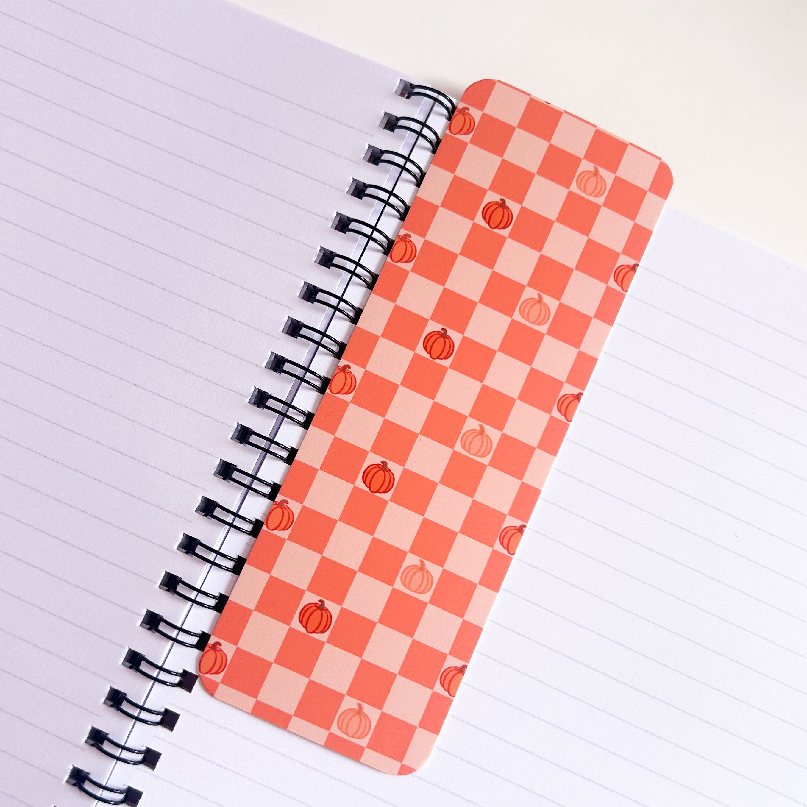 Notebook with a checkered Orange pumpkin bookmark patterned on a white background